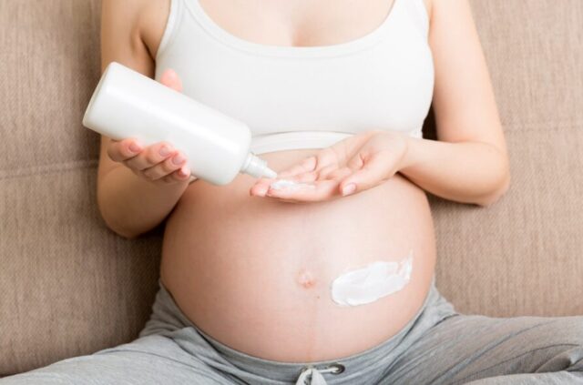 A pregnant woman applying stretch mark cream