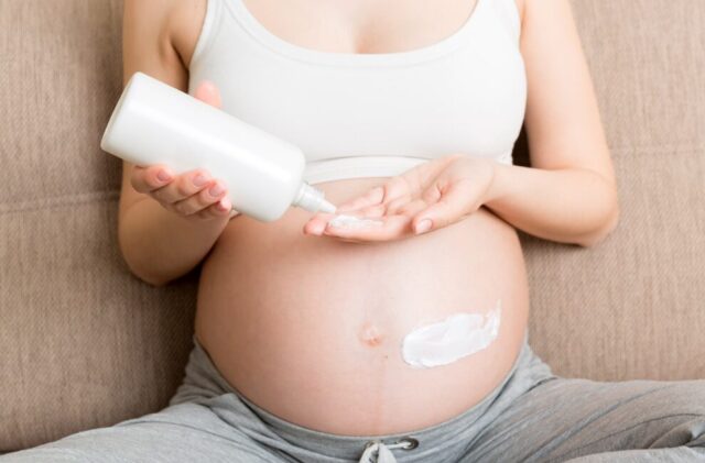 A pregnant woman using stretch mark cream